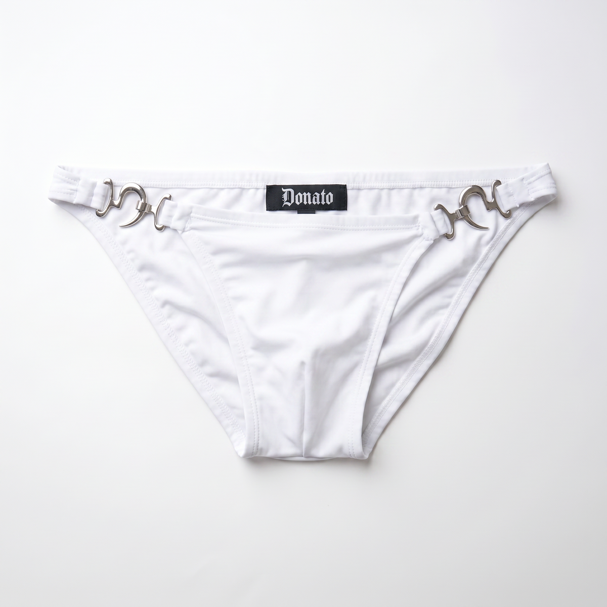 White bikini bottom featuring silver horsebit hardware on the sides and a black central label with the brand name 'Donato' in gothic font, laid flat on a white background.